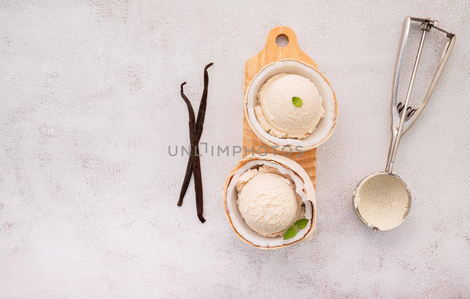 Coconut ice cream flavours in half of coconut setup on white stone background. Summer and Sweet menu concept. by kerdkanno