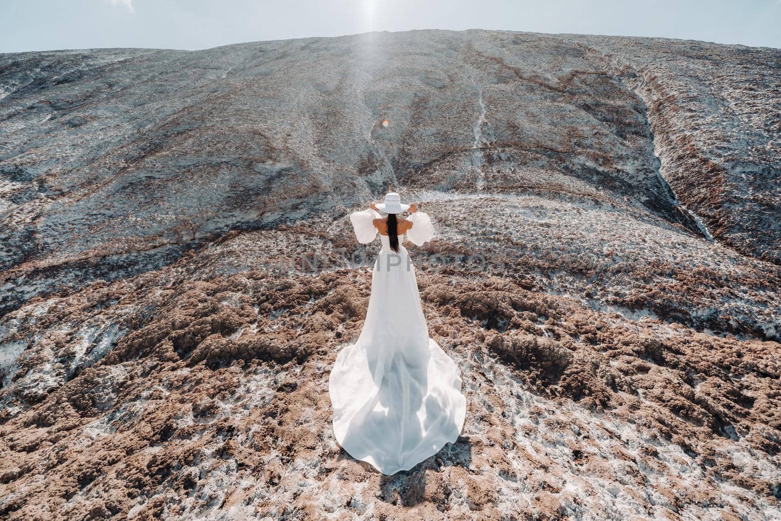 Beautiful unrecognizable bride in a wedding dress and hat on top of the salt mountains. Stunning young bride in a hat. Wedding day. Beautiful portrait of the bride without the groom.