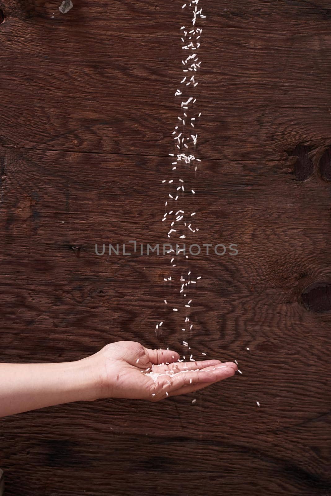 Rice run into hand on wooden background