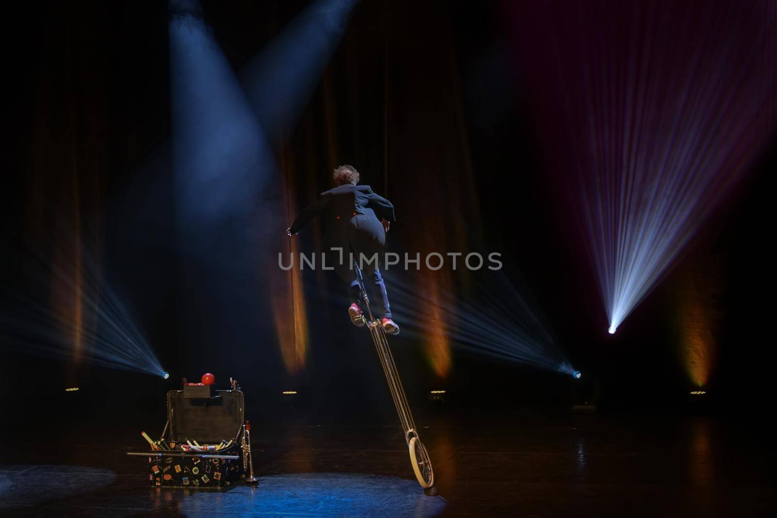 Juggler clown in the circus arena on a unicycle