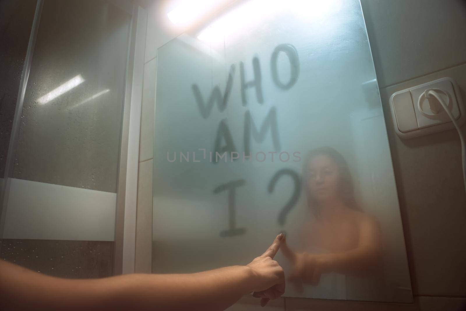Woman writing on the mirror who am I. self awareness, identity or personality concept by DariaKulkova
