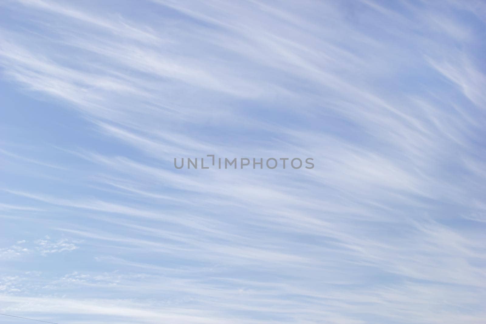 White cirrus clouds on the background blue sky.