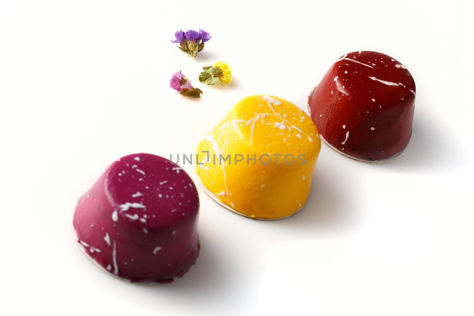 Three multi-colored glazed mini tarts with cream isolated on a white background, close-up