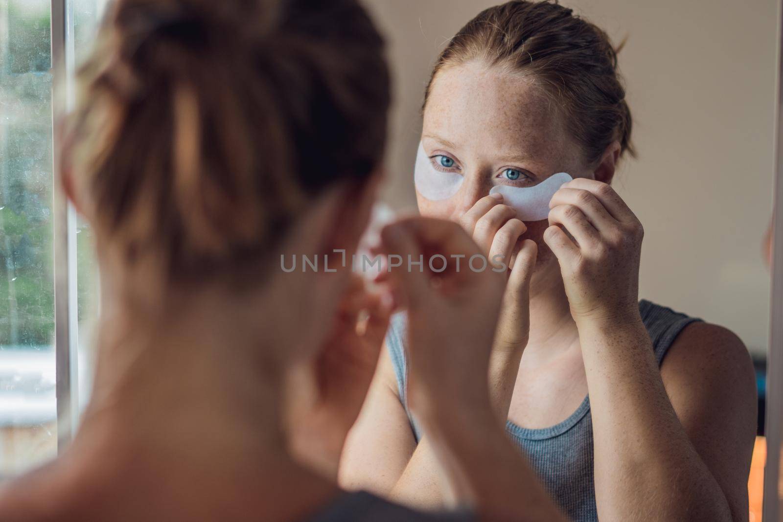 Portrait of Beauty Red-haired woman with eye patches showing an effect of perfect skin. Spa Girl by galitskaya