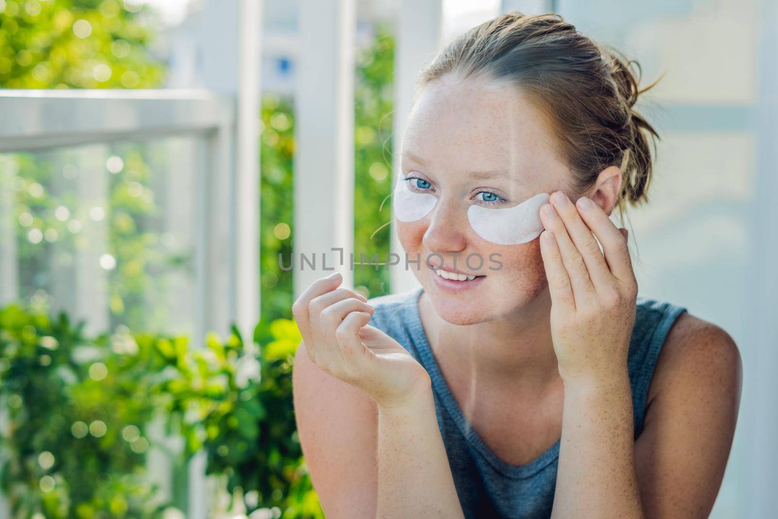 Portrait of Beauty Red-haired woman with eye patches showing an effect of perfect skin. Spa Girl.