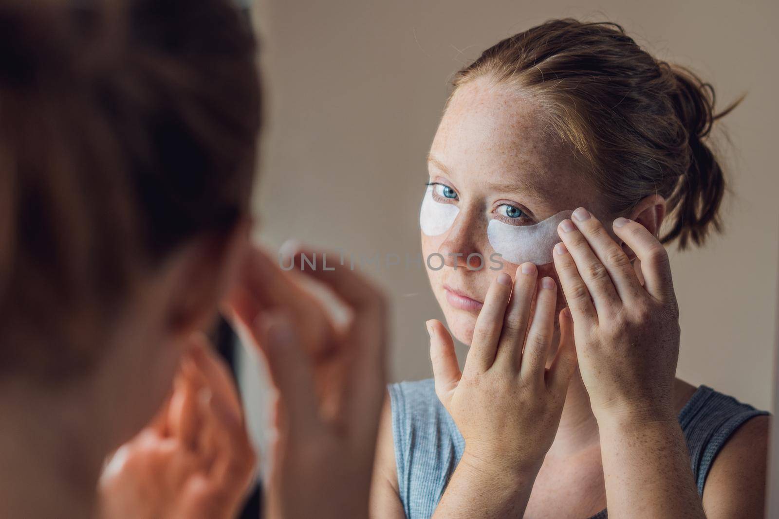 Portrait of Beauty Red-haired woman with eye patches showing an effect of perfect skin. Spa Girl.