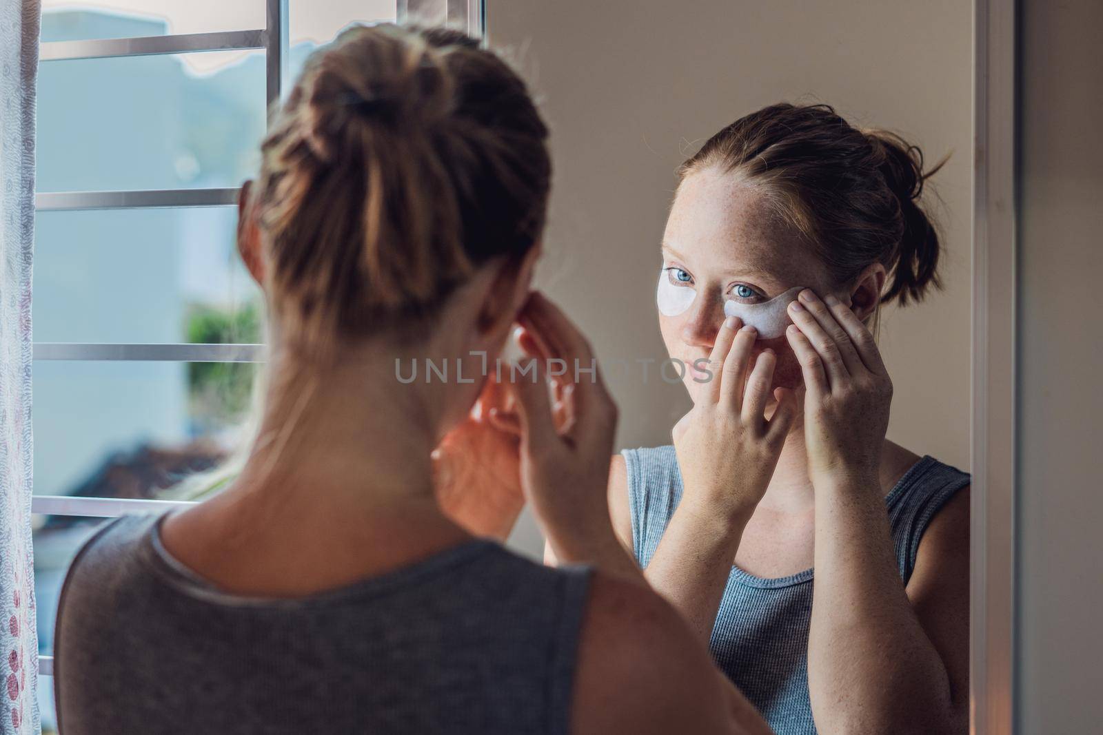 Portrait of Beauty Red-haired woman with eye patches showing an effect of perfect skin. Spa Girl.