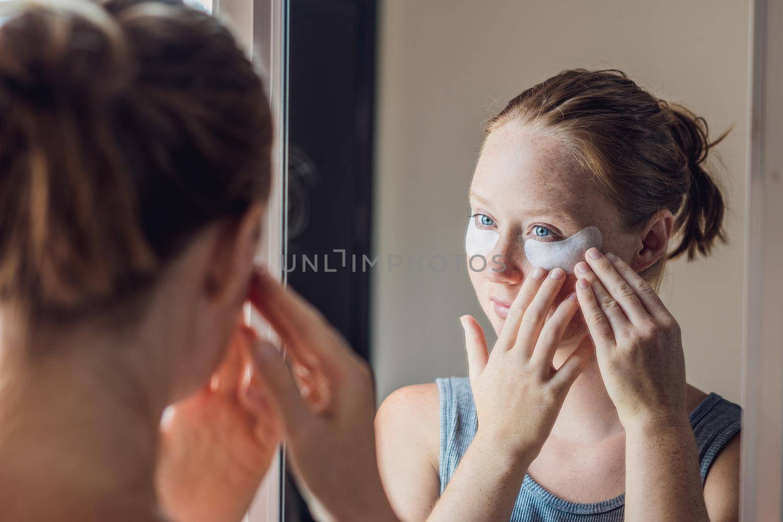 Portrait of Beauty Red-haired woman with eye patches showing an effect of perfect skin. Spa Girl.