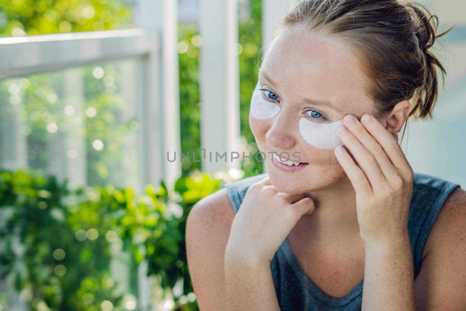 Portrait of Beauty Red-haired woman with eye patches showing an effect of perfect skin. Spa Girl.