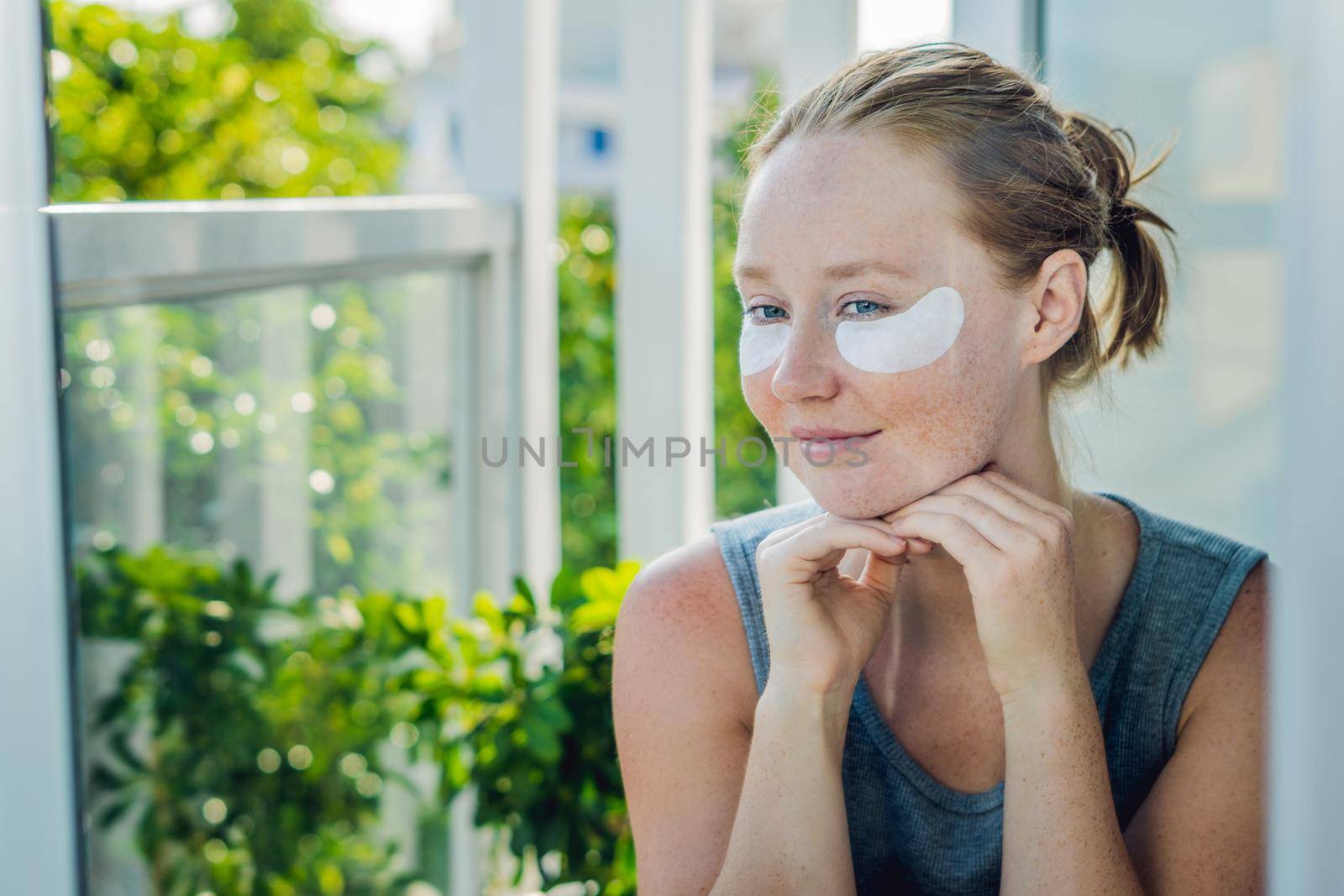 Portrait of Beauty Red-haired woman with eye patches showing an effect of perfect skin. Spa Girl.