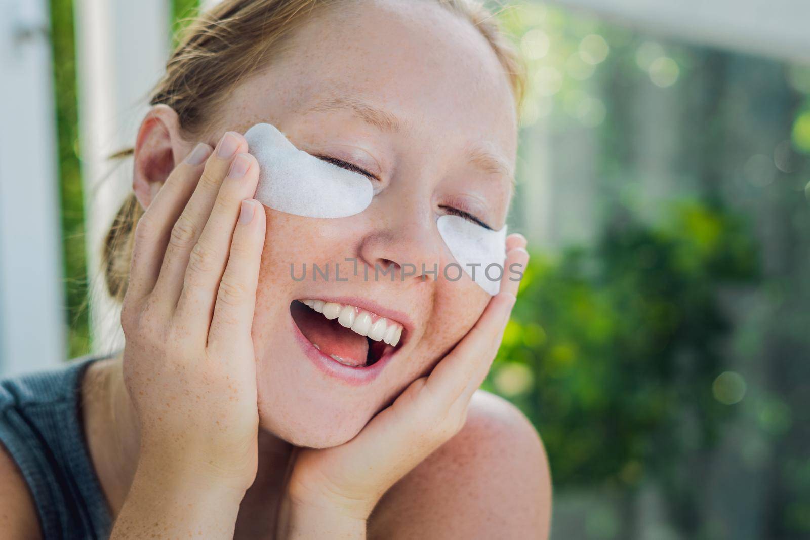 Portrait of Beauty Red-haired woman with eye patches showing an effect of perfect skin. Spa Girl.