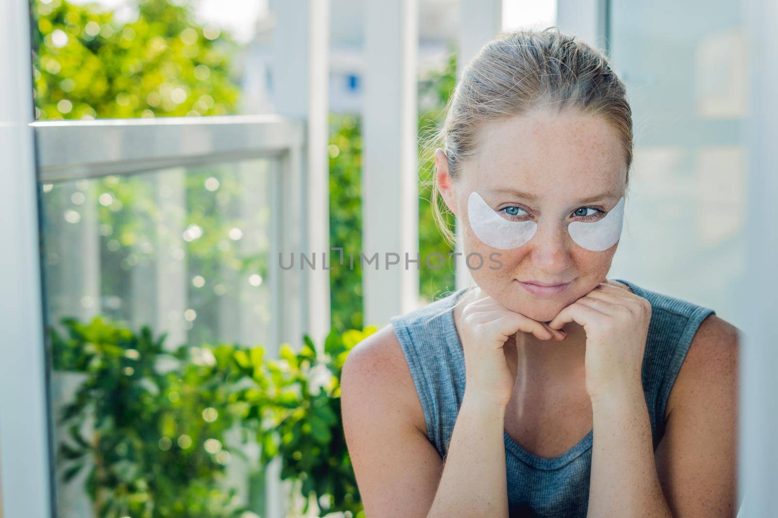 Portrait of Beauty Red-haired woman with eye patches showing an effect of perfect skin. Spa Girl.