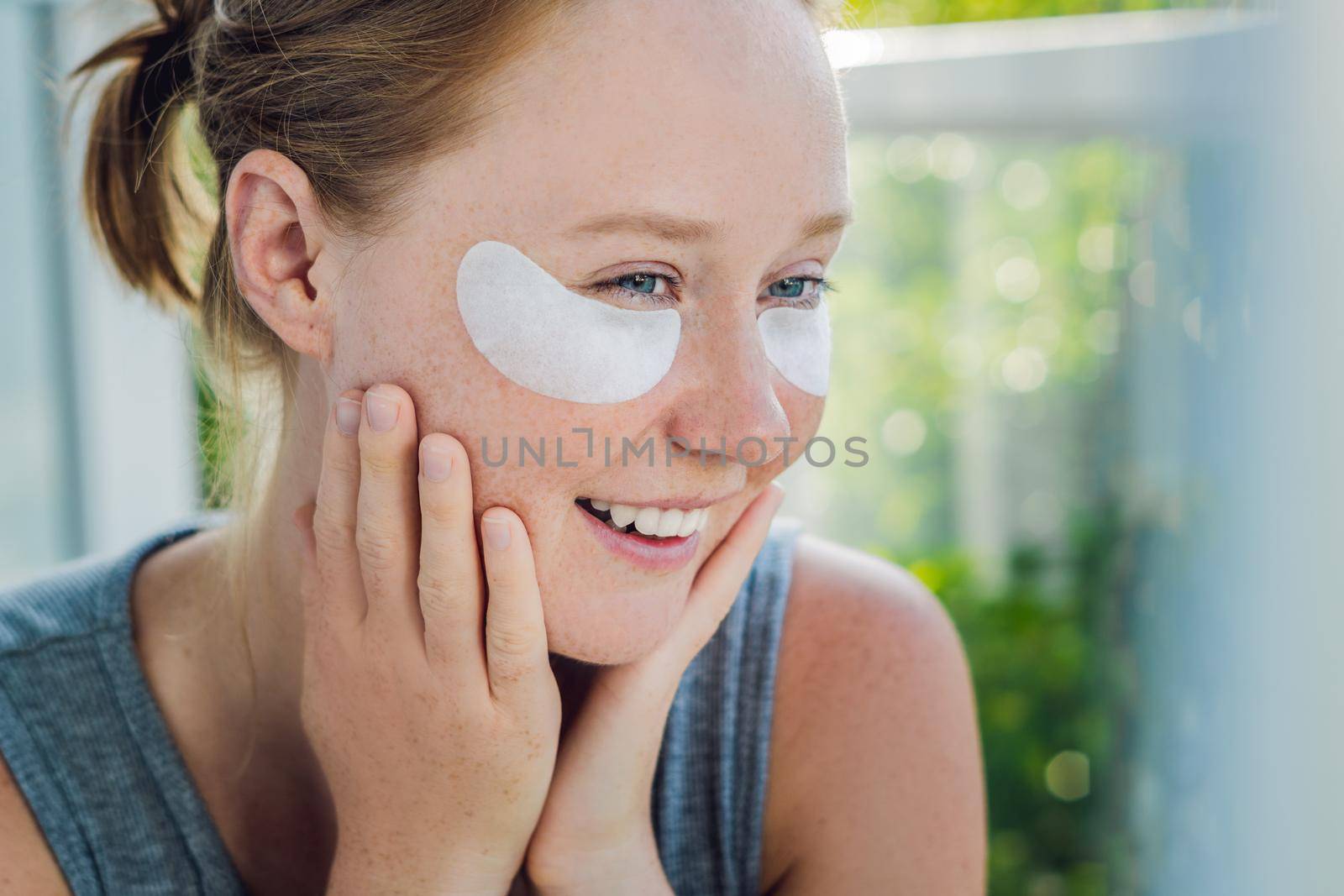 Portrait of Beauty Red-haired woman with eye patches showing an effect of perfect skin. Spa Girl.