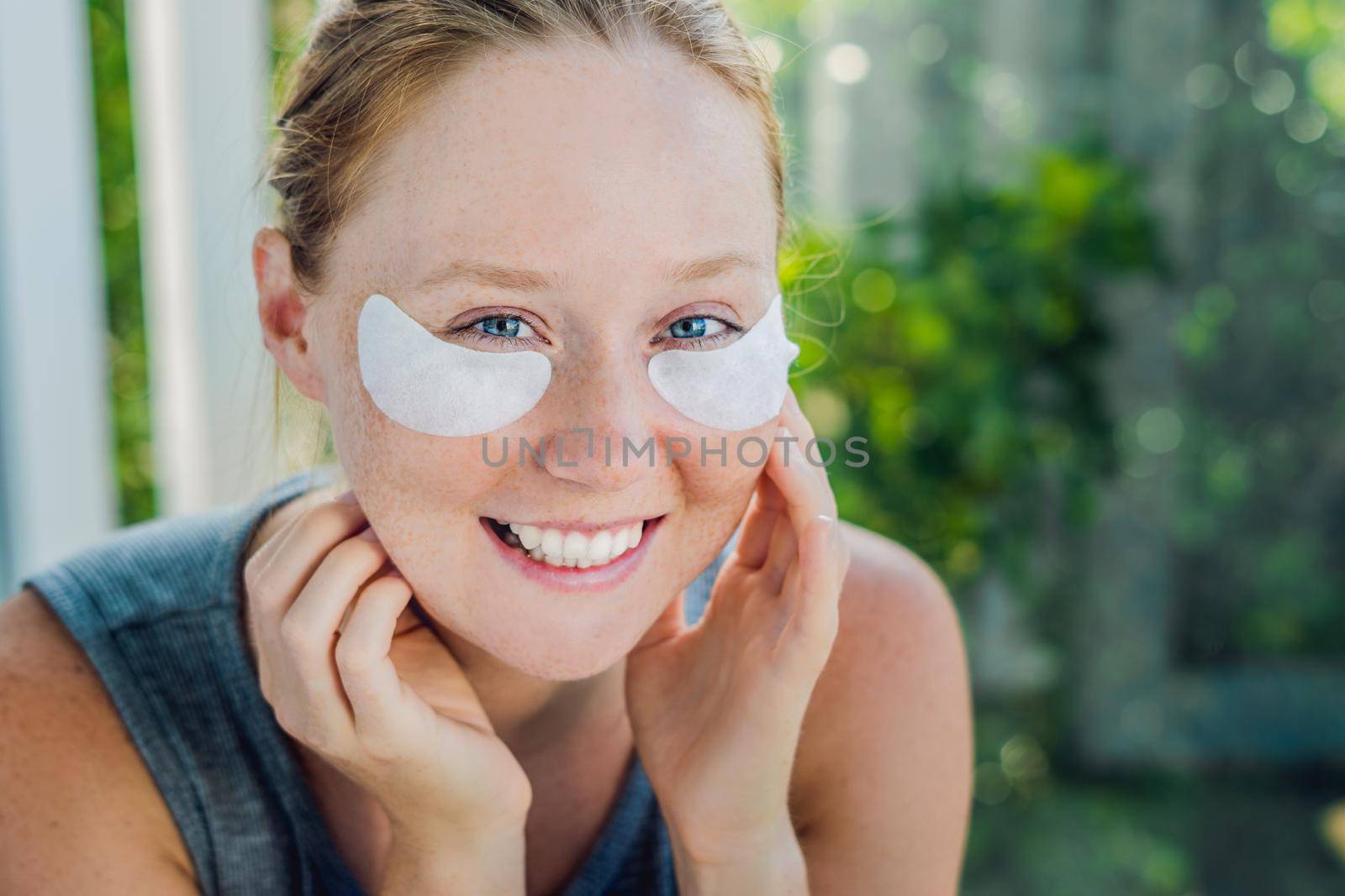 Portrait of Beauty Red-haired woman with eye patches showing an effect of perfect skin. Spa Girl.