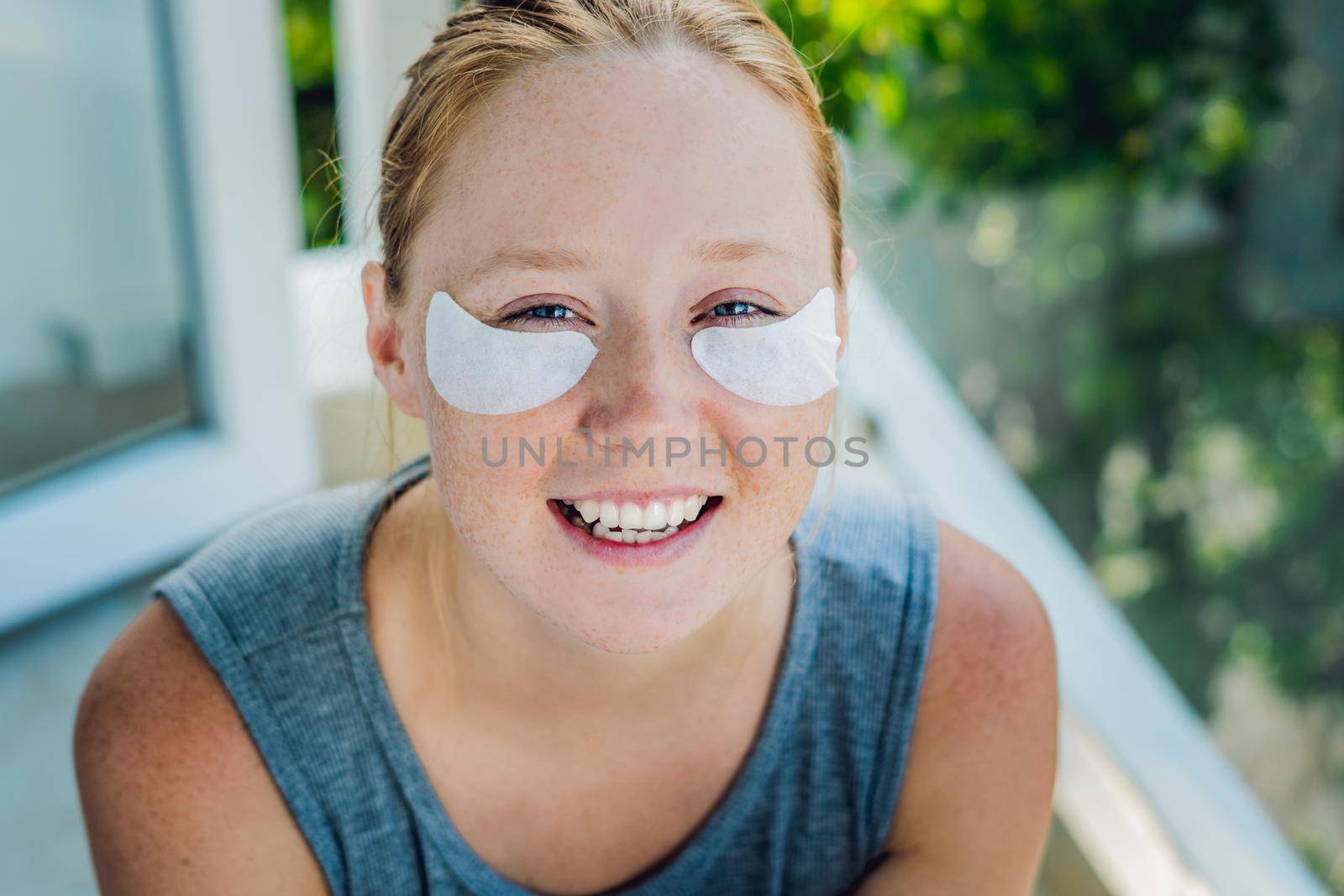 Portrait of Beauty Red-haired woman with eye patches showing an effect of perfect skin. Spa Girl.