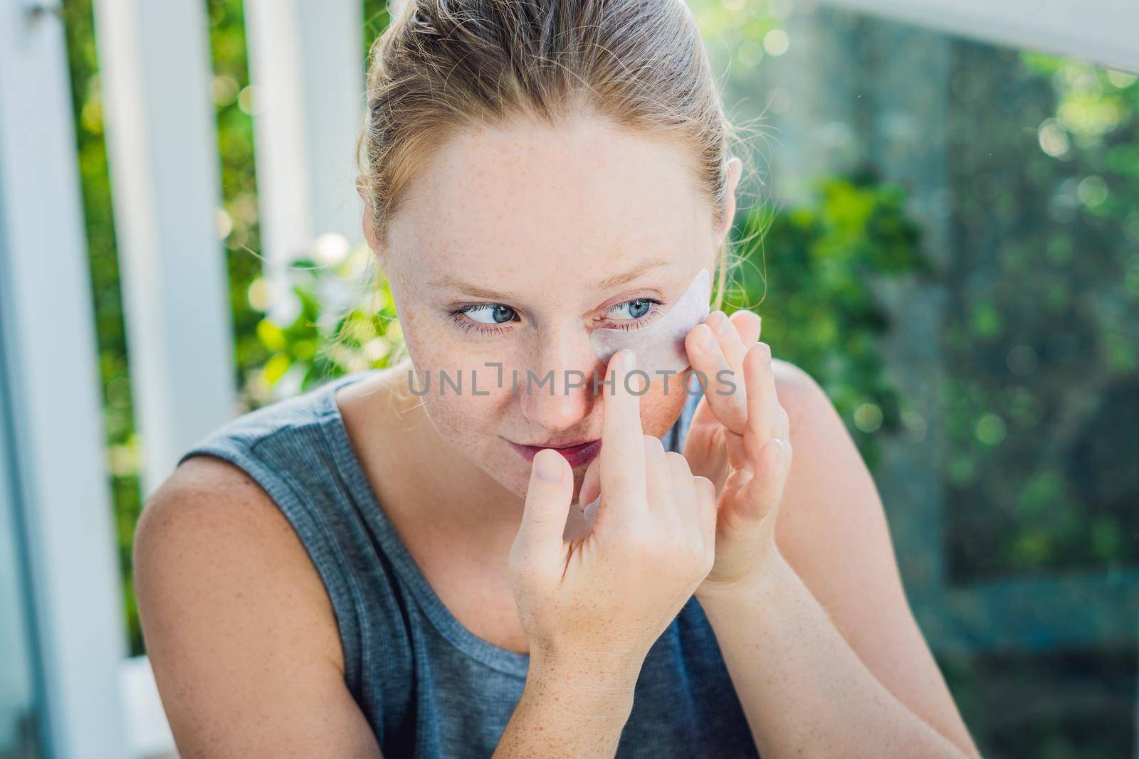 Portrait of Beauty Red-haired woman with eye patches showing an effect of perfect skin. Spa Girl.