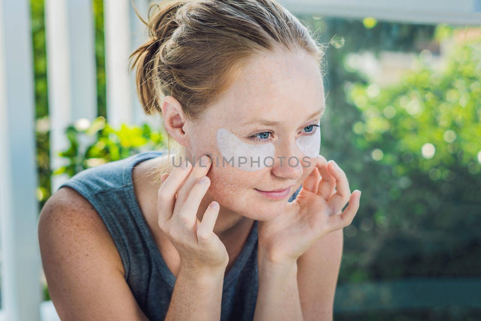 Portrait of Beauty Red-haired woman with eye patches showing an effect of perfect skin. Spa Girl.