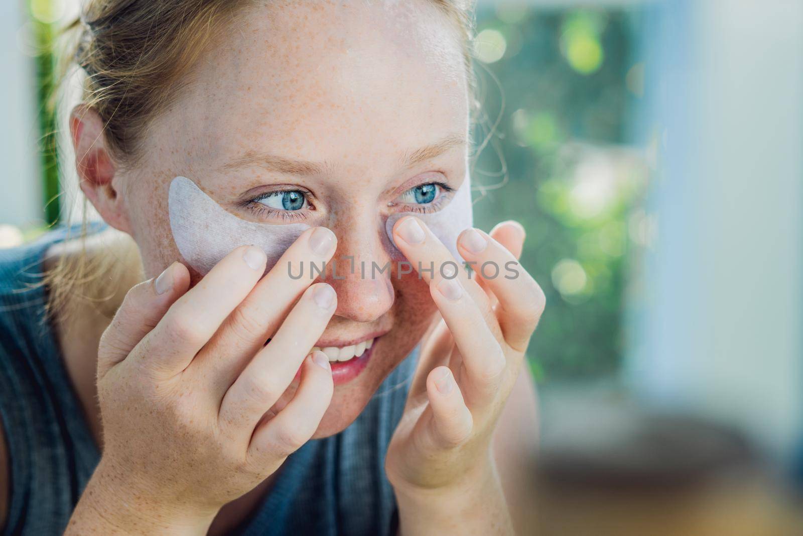 Portrait of Beauty Red-haired woman with eye patches showing an effect of perfect skin. Spa Girl.