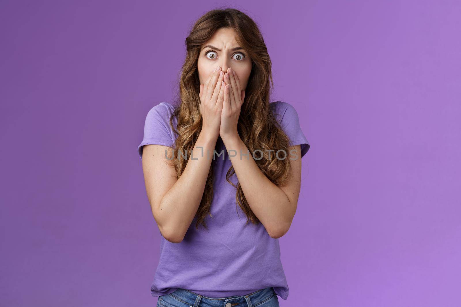 Shocked concerned ambushed scared intense girl gasping hold scream cover mouth stare camera frightened speechless learn terrible bad news stand purple background distressed upset.