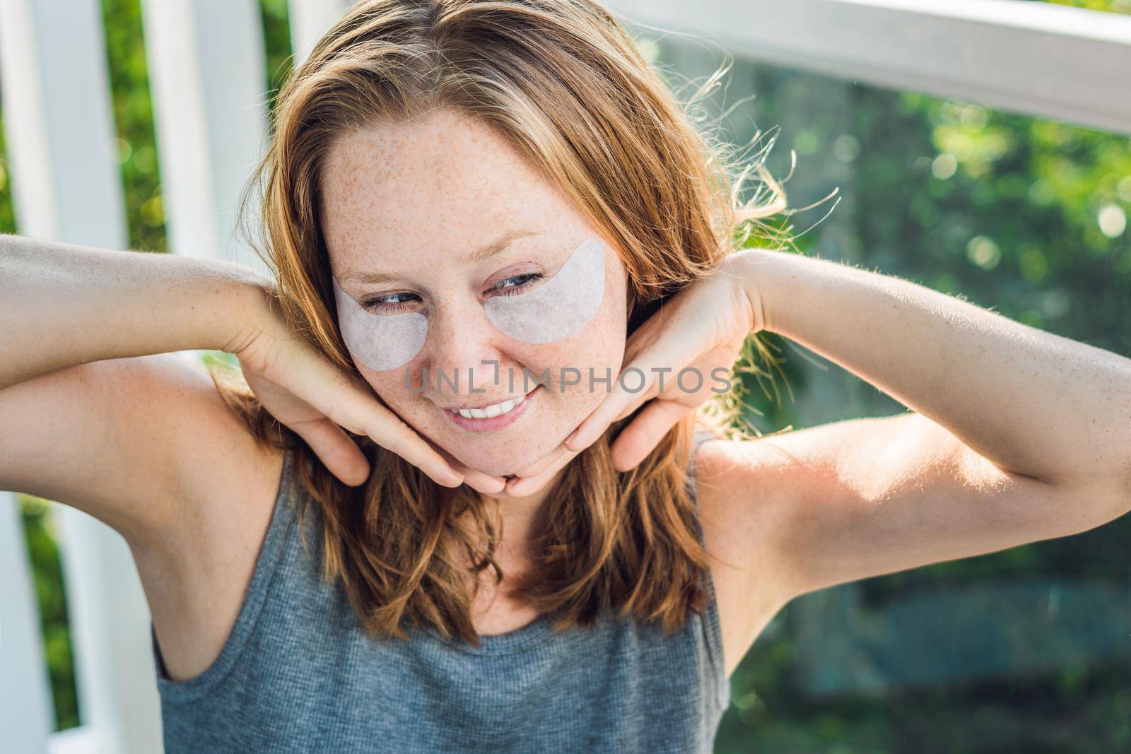 Portrait of Beauty Red-haired woman with eye patches showing an effect of perfect skin. Spa Girl.