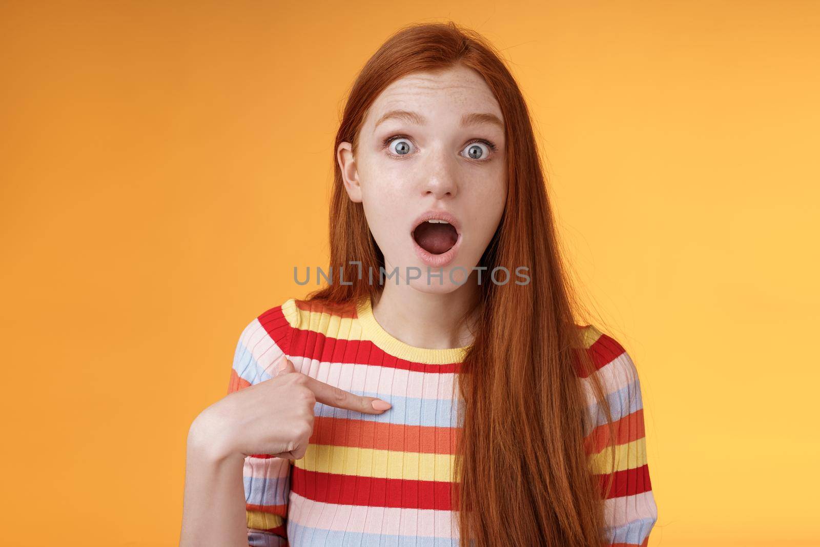 Shocked silly surprised redhead cute girl gasping drop jaw stunned stare camera full disbelief pointing herself cannot believe chosen picked participate event standing impressed orange background by Benzoix