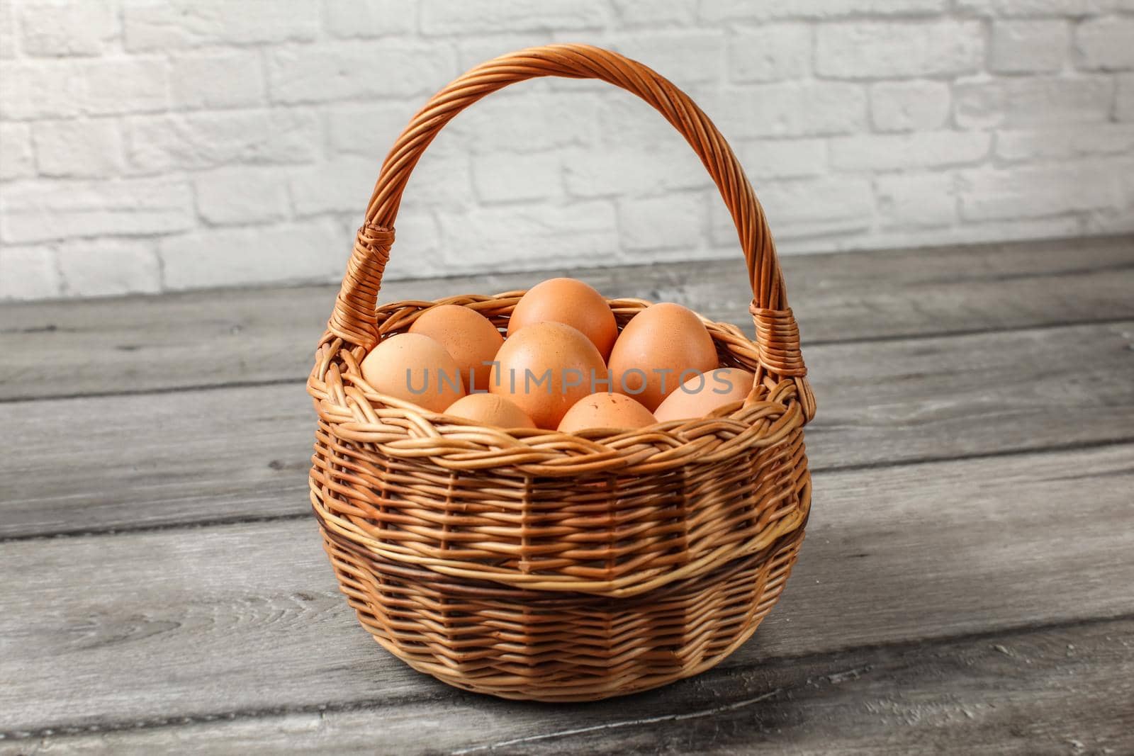 Eggs in wicker basket placed on gray wood desk by the wall.