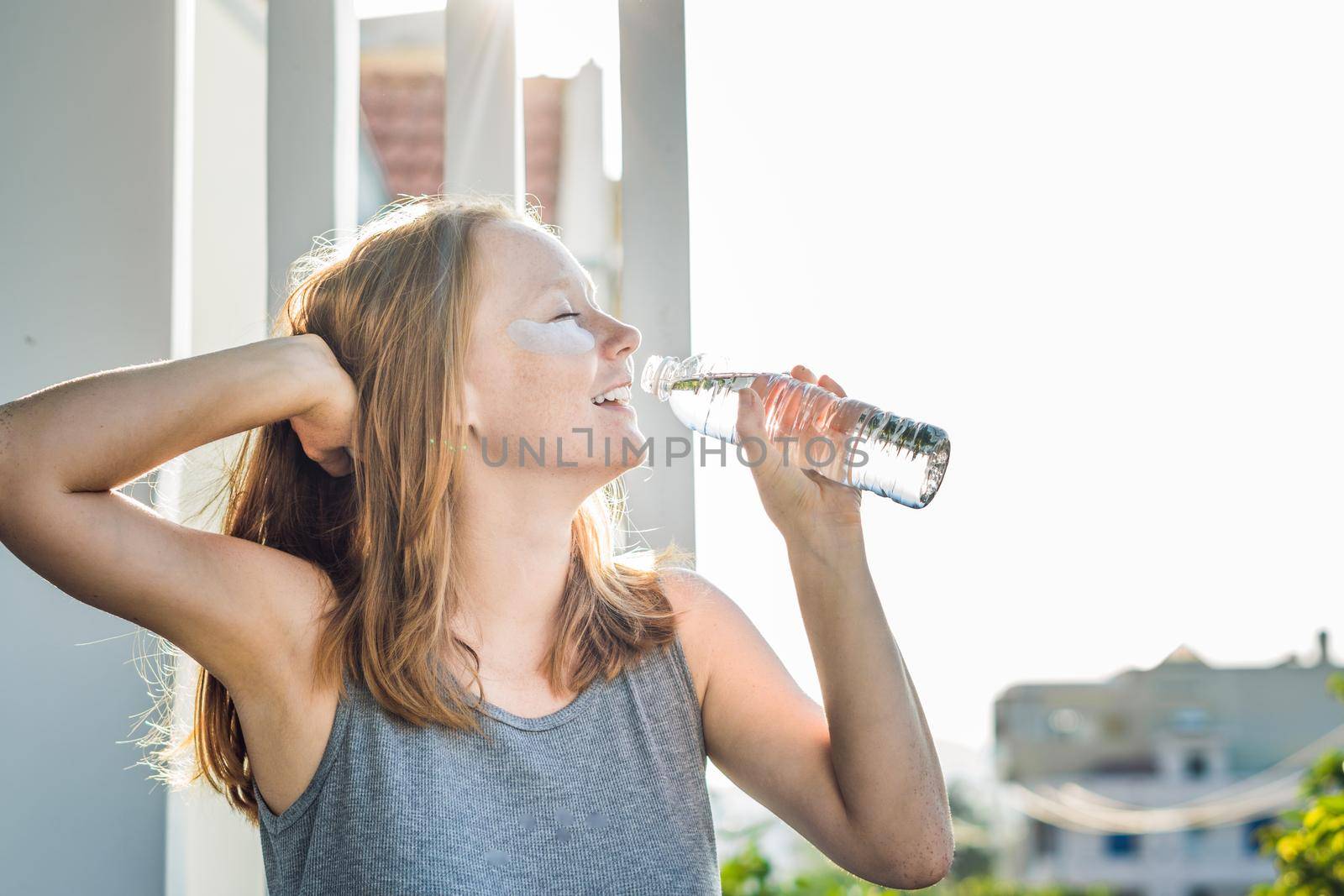 Portrait of Beauty Red-haired woman with eye patches drinks water. Spa Girl.