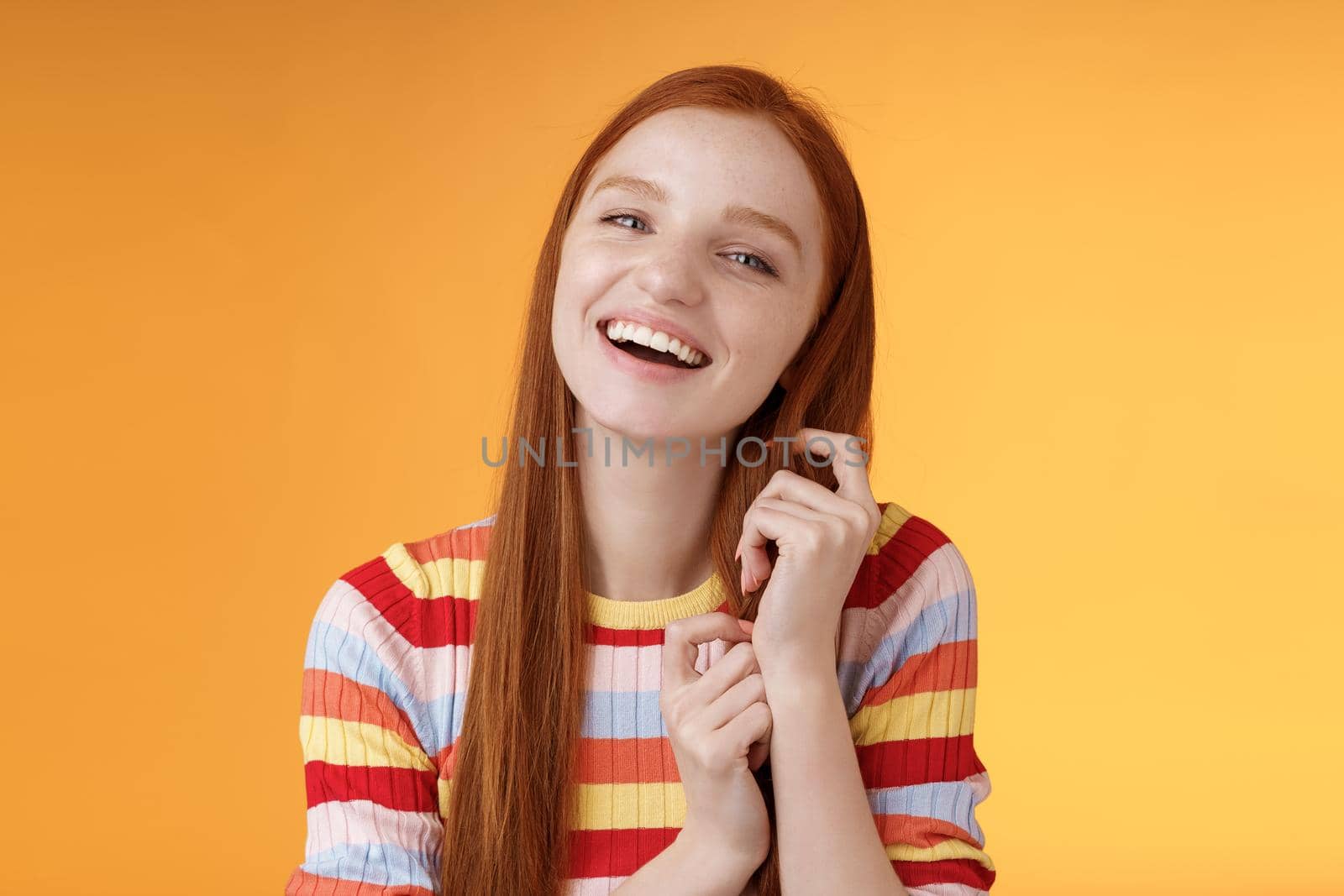 Silly good-looking flirty lively redhead young girl laughing playing coquettish ginger hair strand chuckling amused funny boyfriend jokes having fun awesome romantic date, orange background.