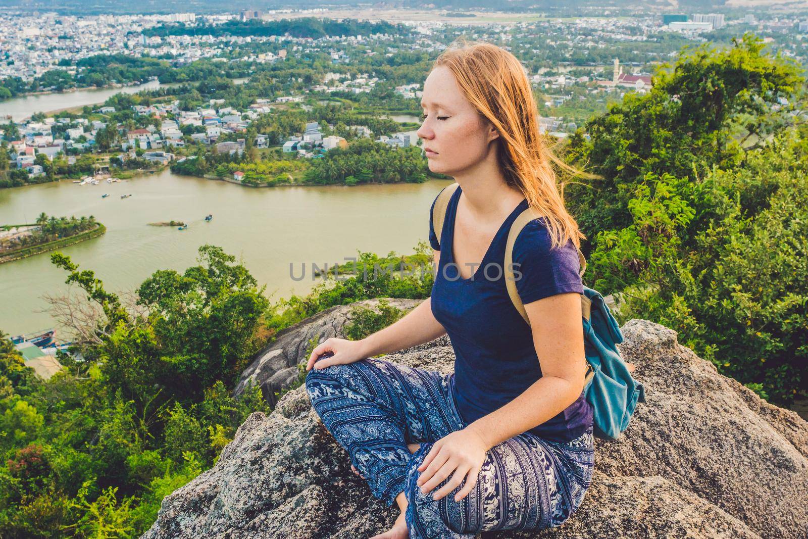 Young woman meditating over ancient city landscape on sunrise Copy space.