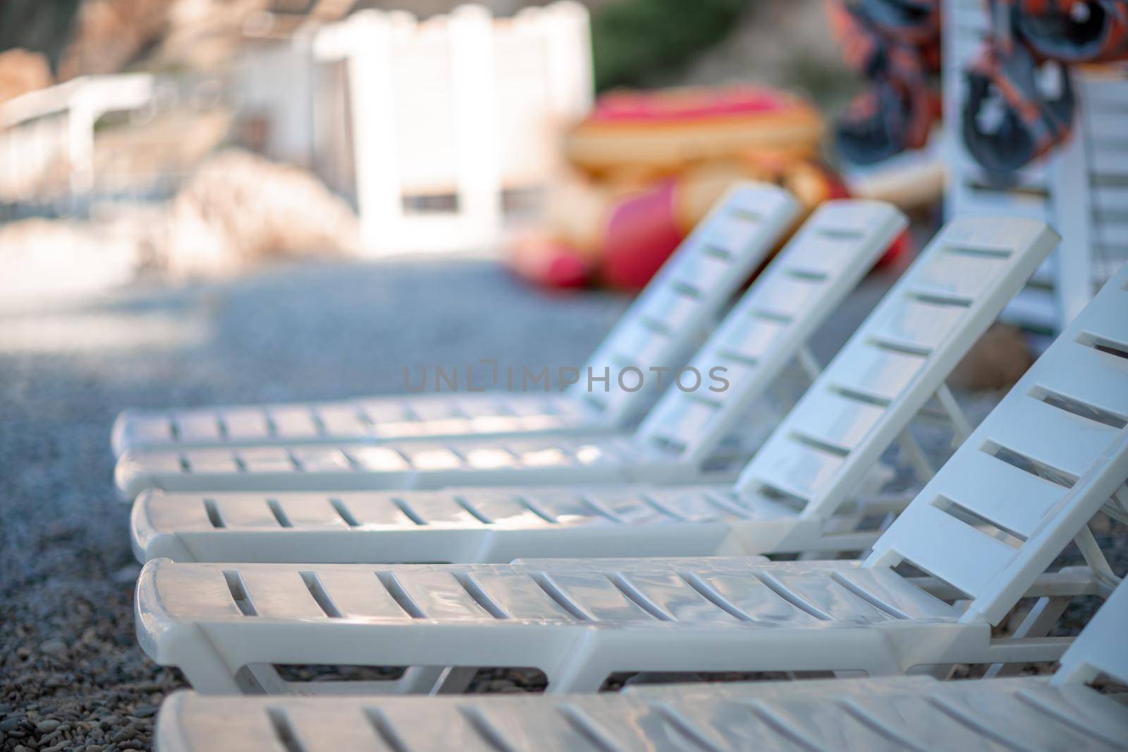 Several white sun loungers on a deserted beach. The perfect vacation concept. by Matiunina