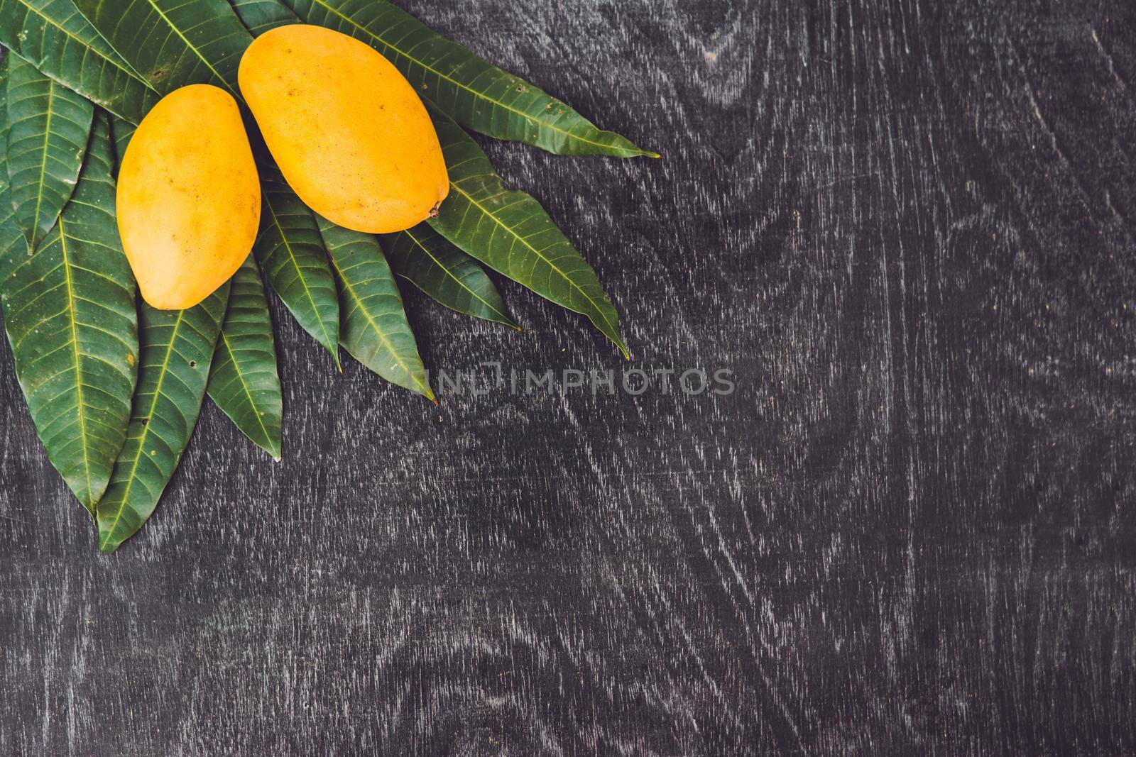 Mango and mango leaves on an old wooden background.