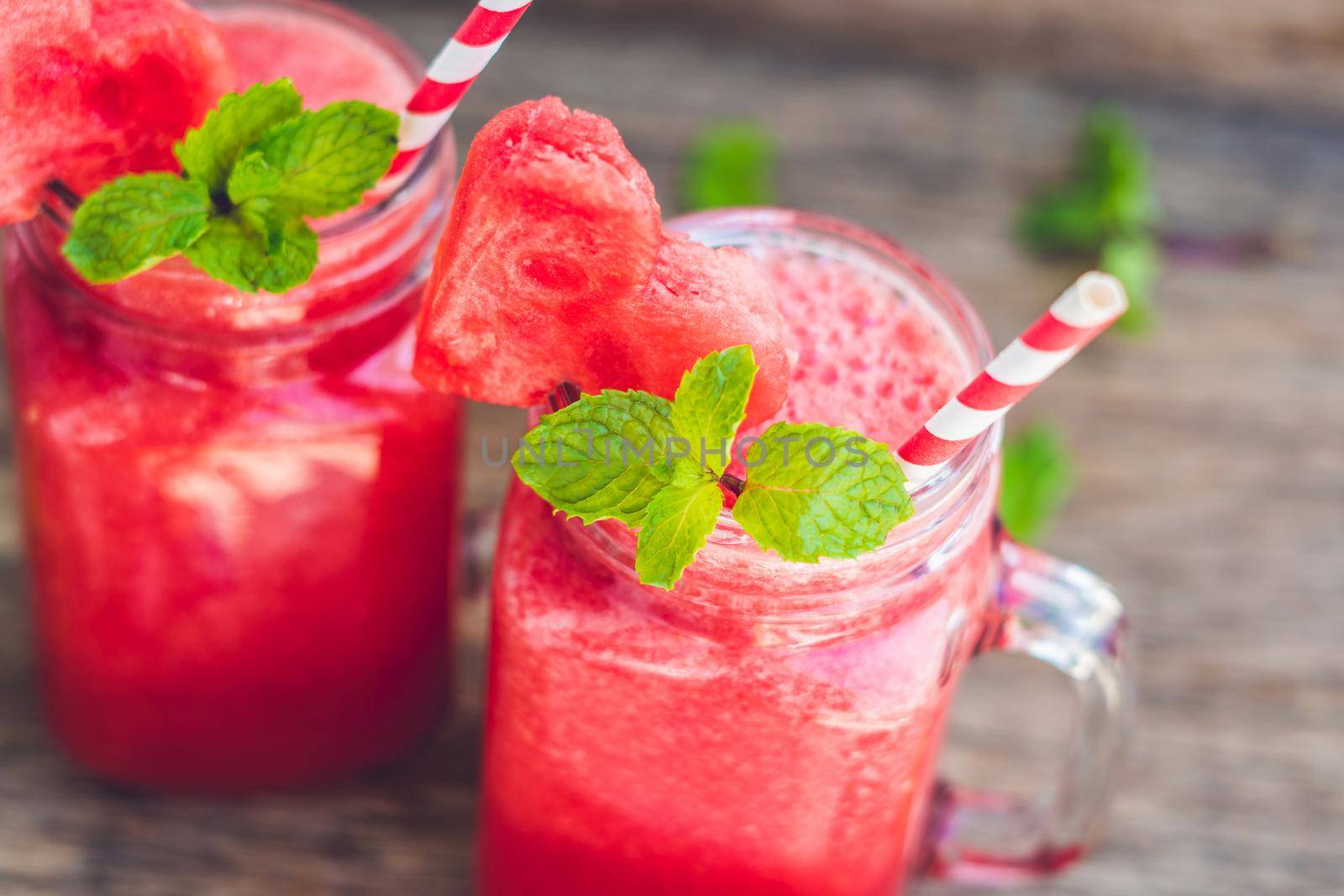 Healthy watermelon smoothie in Mason jars with mint and striped straws on a wood background by galitskaya
