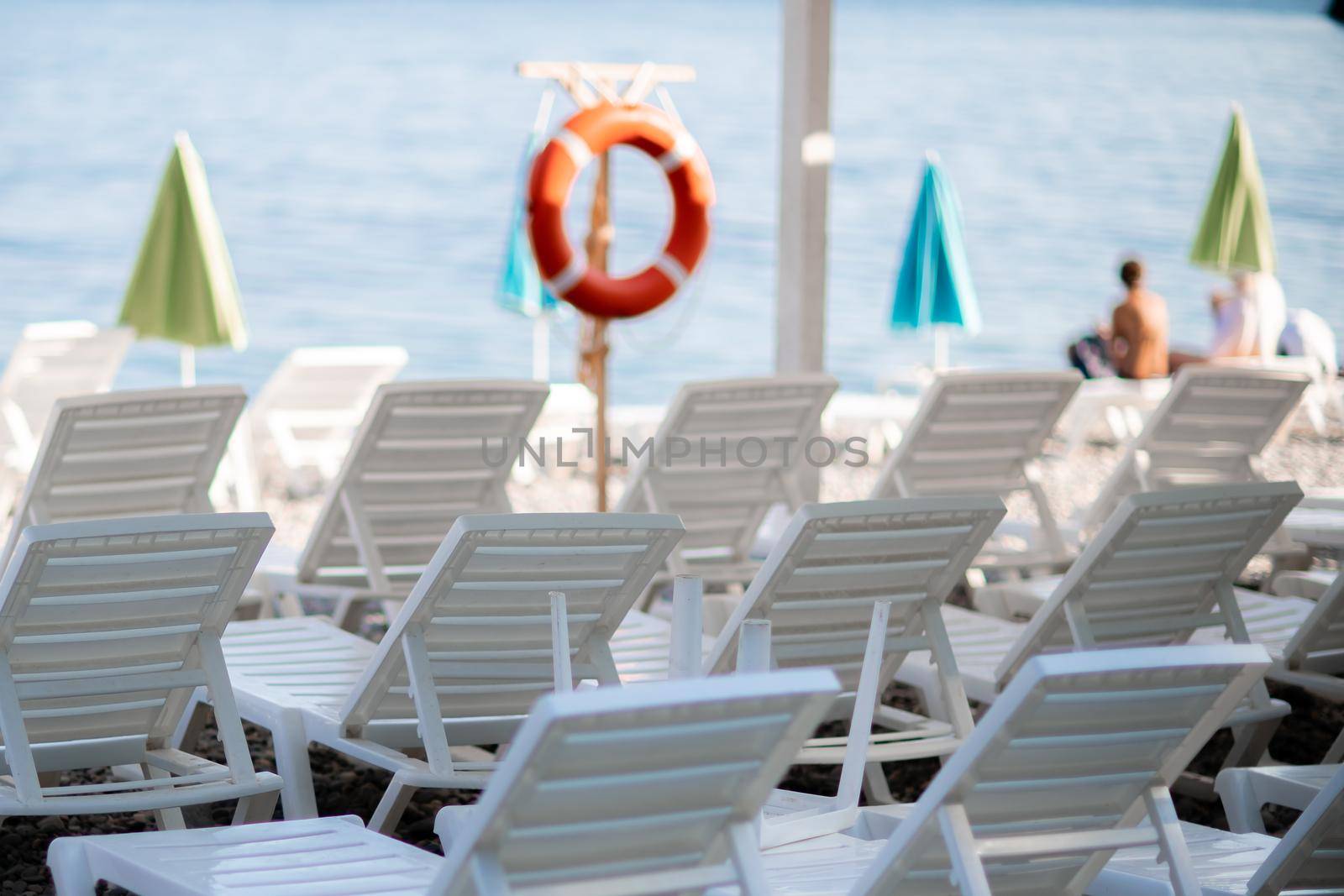 Several white sun loungers and an umbrella on a deserted beach. The perfect vacation concept