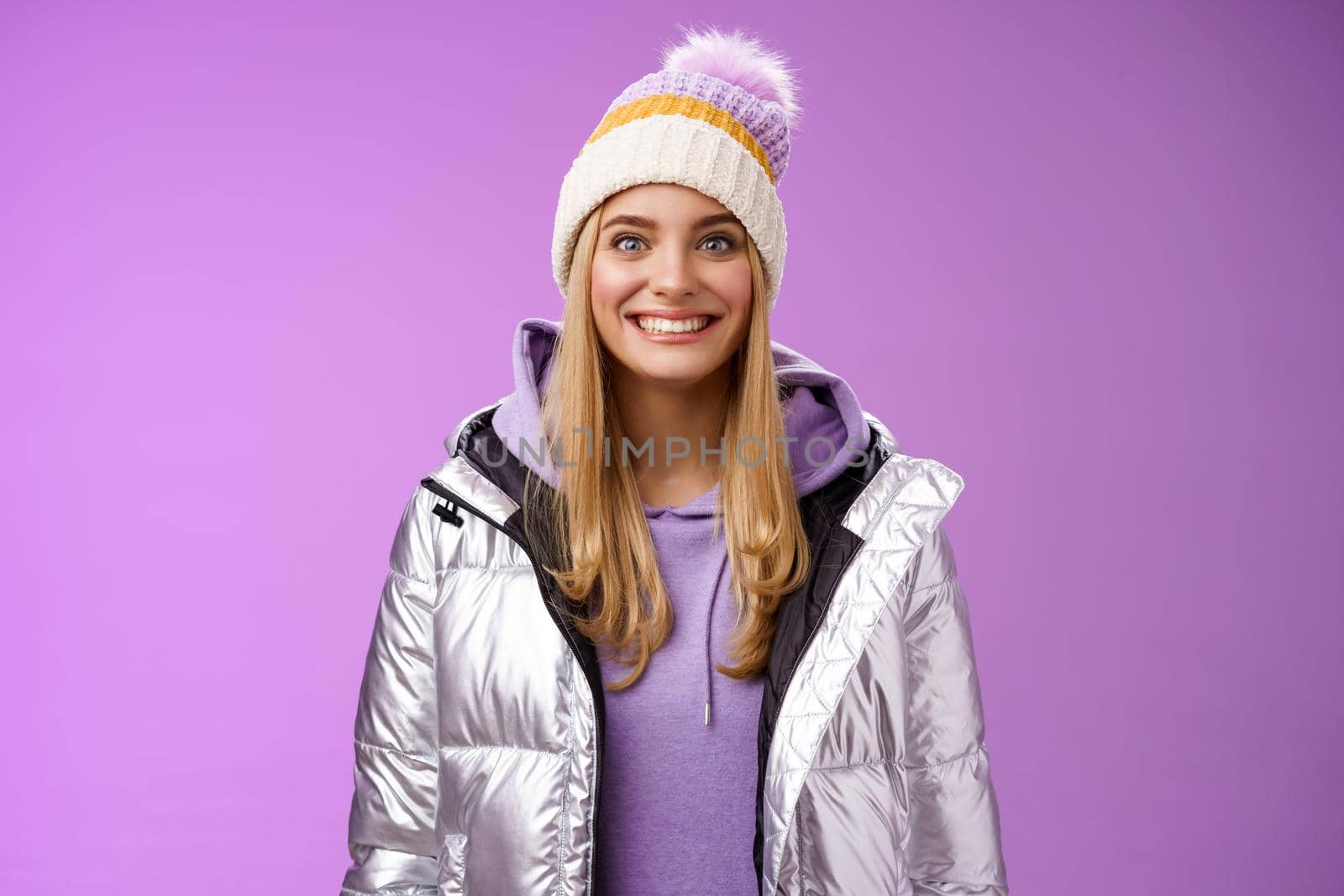 Amused fascinated attractive excited blond woman stepping skis first time feel temptation thrill joyfully smiling widen eyes impressed cannot wait learn snowboarding standing silver jacket.