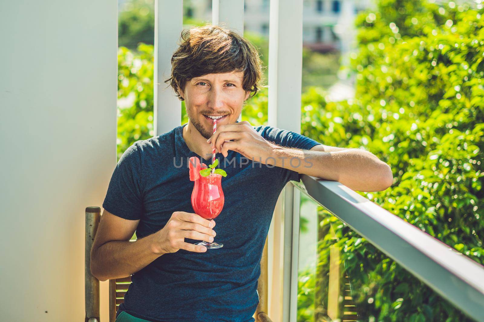 Man is holding Healthy watermelon smoothie with mint and striped straws on a wood background by galitskaya