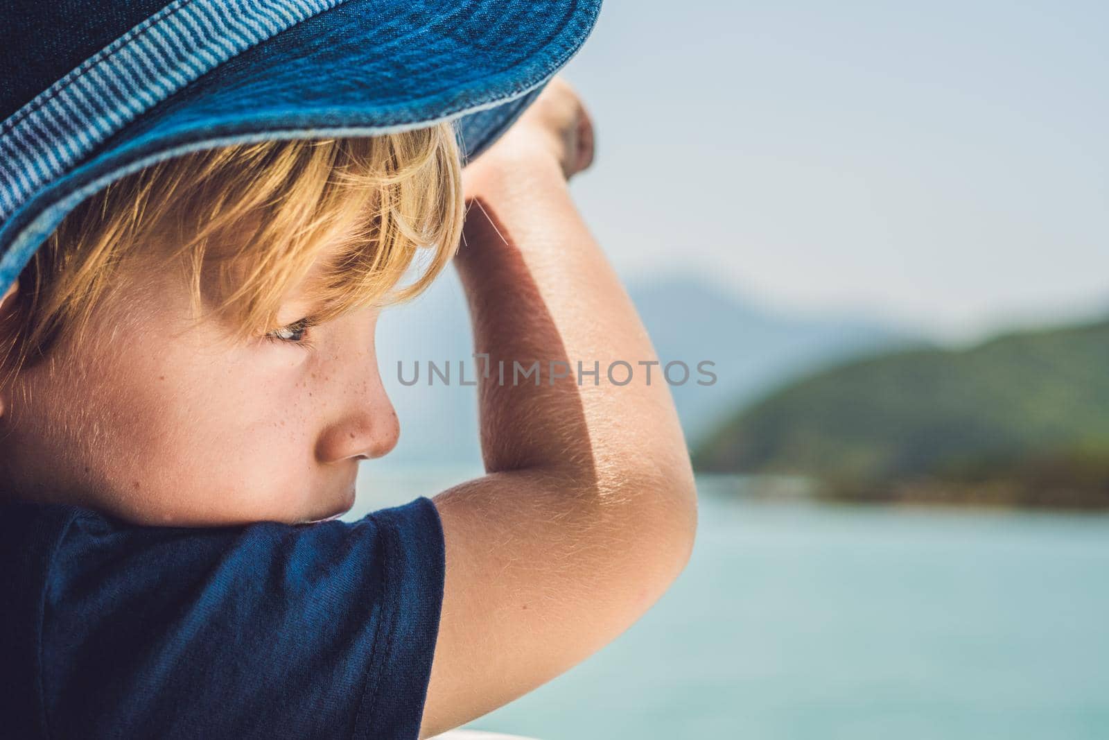 Adorable boy looking to the blue sea from yacht board in sunny day.