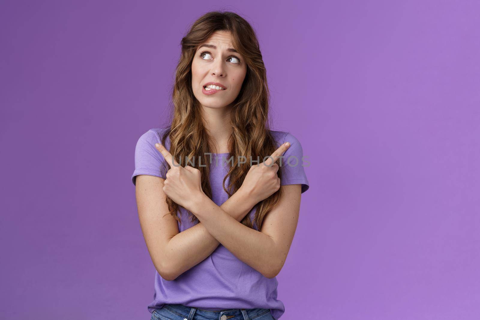 Hesitant unsure worried girl complicated make difficuly choice frowning nervously deciding look away pointing sideways cross hands chest left right anxiously choosing doubtful purple background.