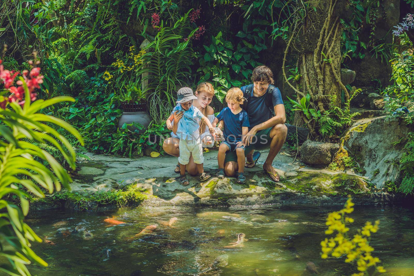 happy family feeding colorful Catfish in tropical pond.