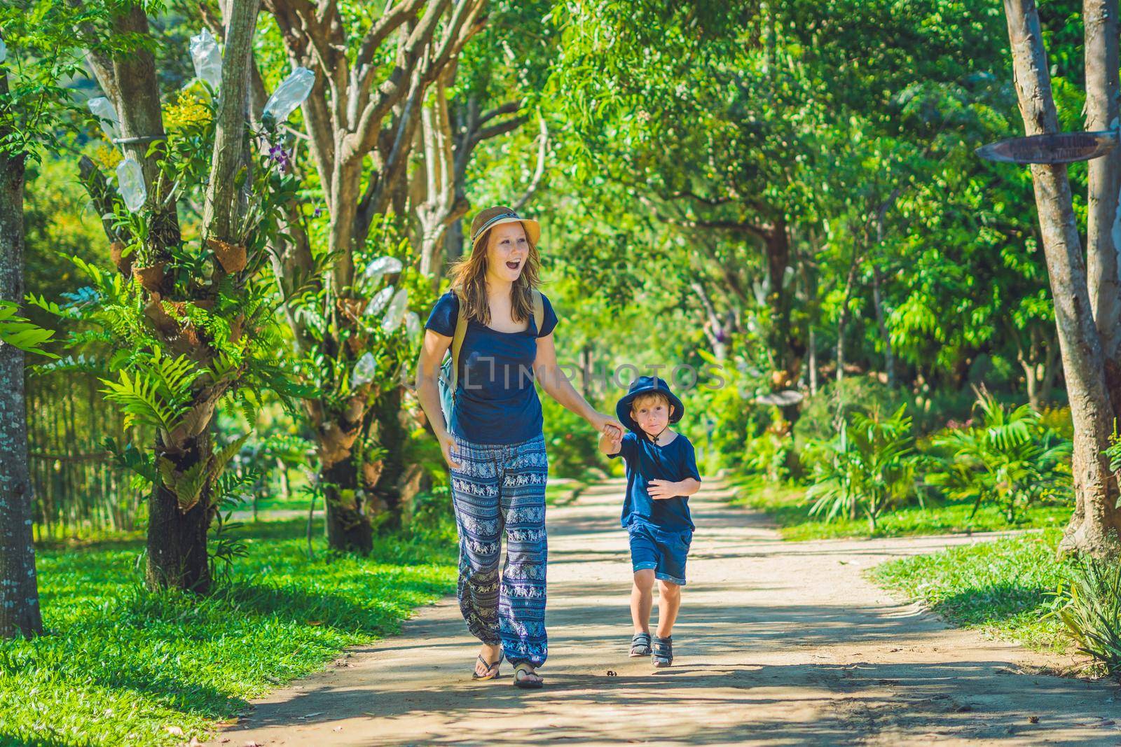 Mom and son are walking in the tropical park.