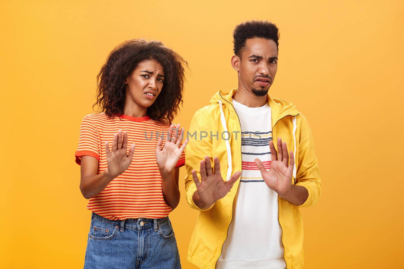 Two african american stylish friends hanging around interrupted by weird guy offering strange proposal shaking hands near chest in refusal and rejection gesture grimacing from aversion and dislike by Benzoix