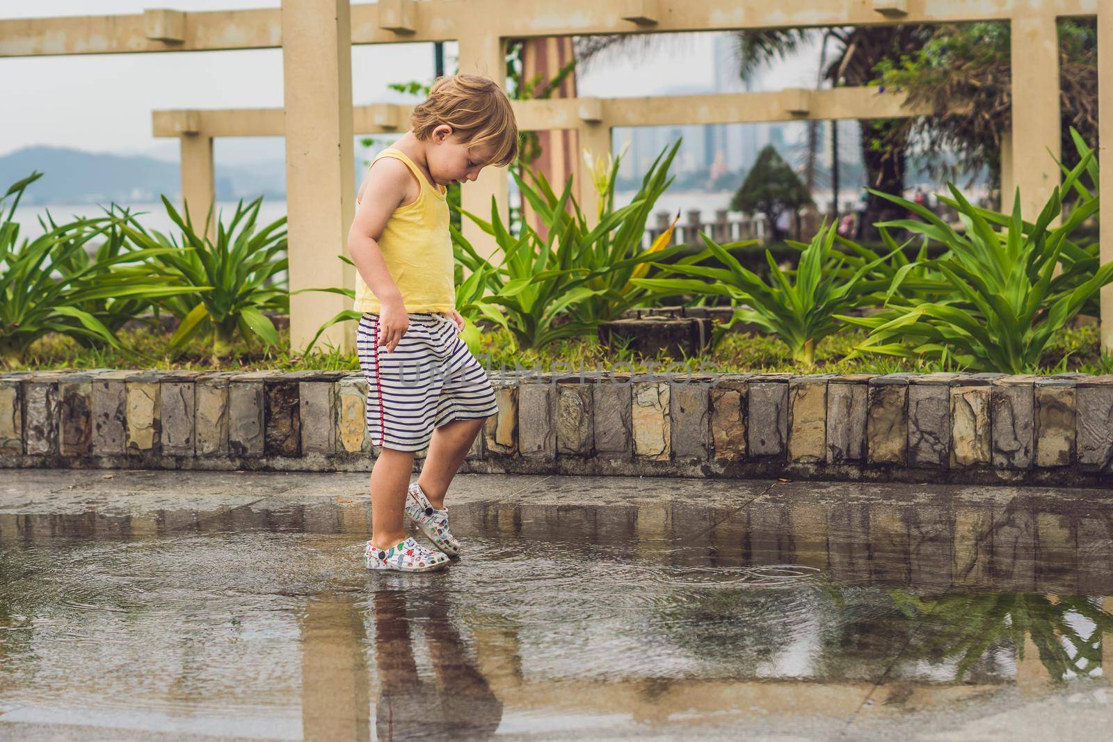 Little boy runs through a puddle. summer outdoor by galitskaya