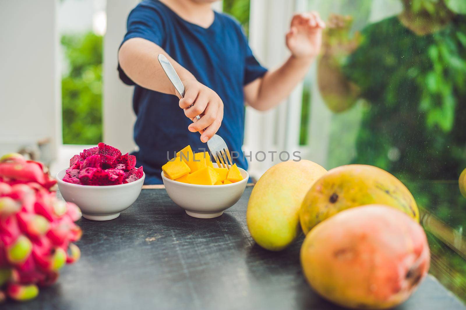 Little cute boy eating mango on the terrace.