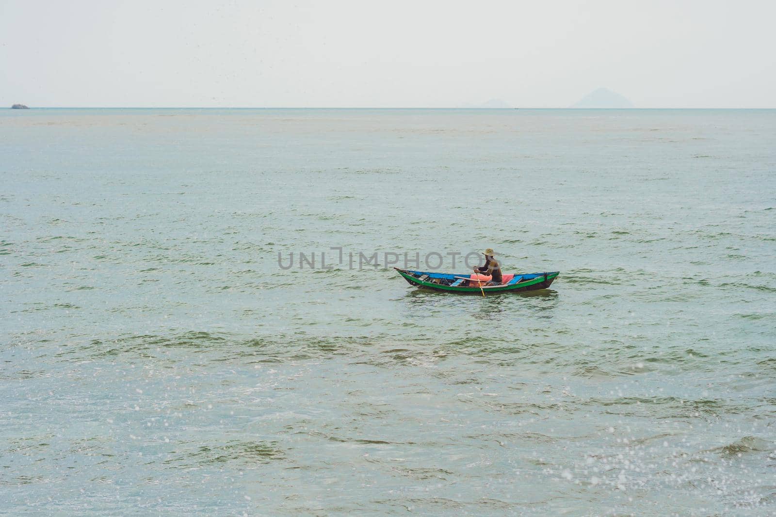 Vietnamese fisherman swims in a boat over the raging sea.