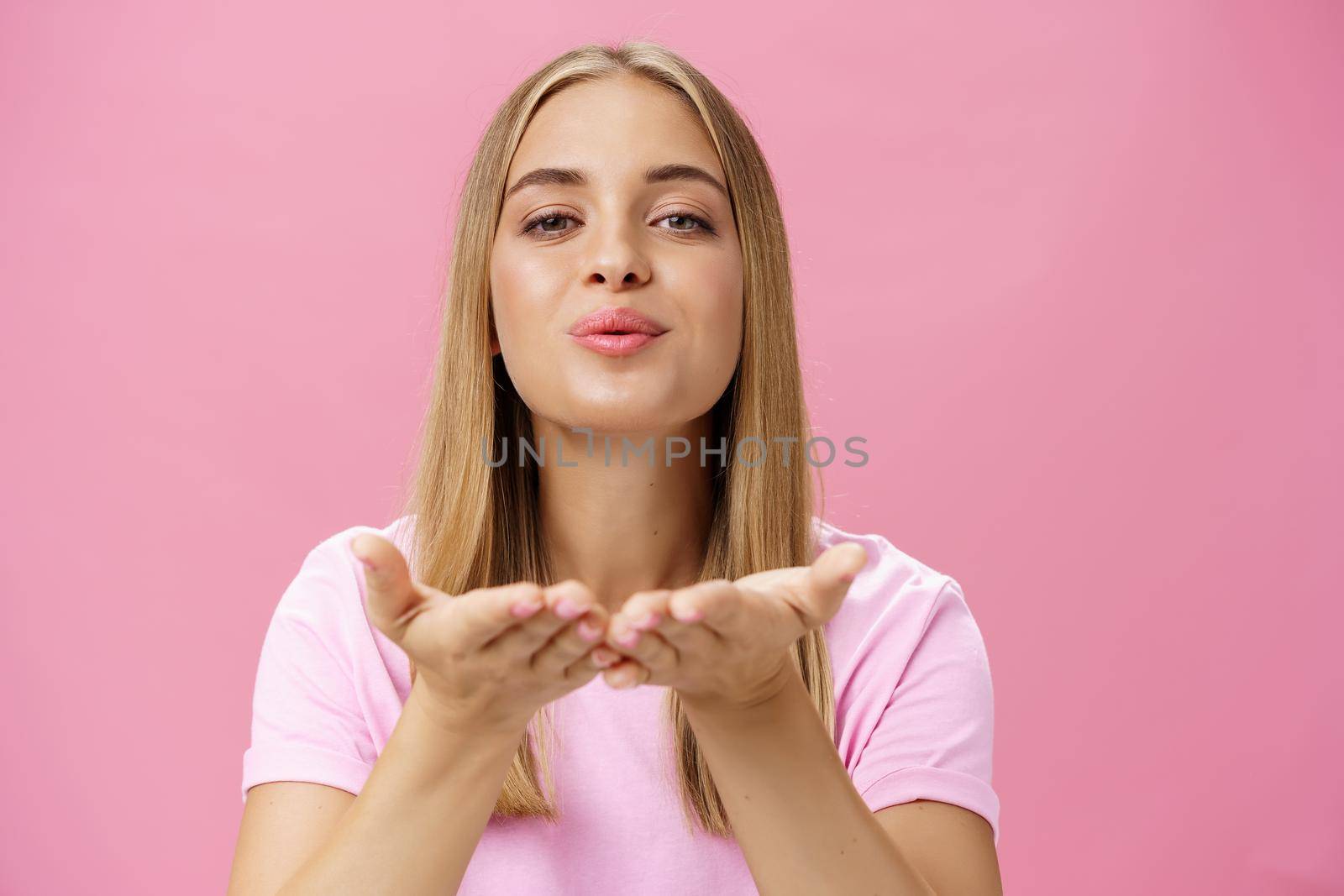 Spreading love to world. Portrait of charming sensual and tender romantic girlfriend holding palms over chest folding lips raising head and sending air kiss at camera with passion and romance. Body language and relationship concept