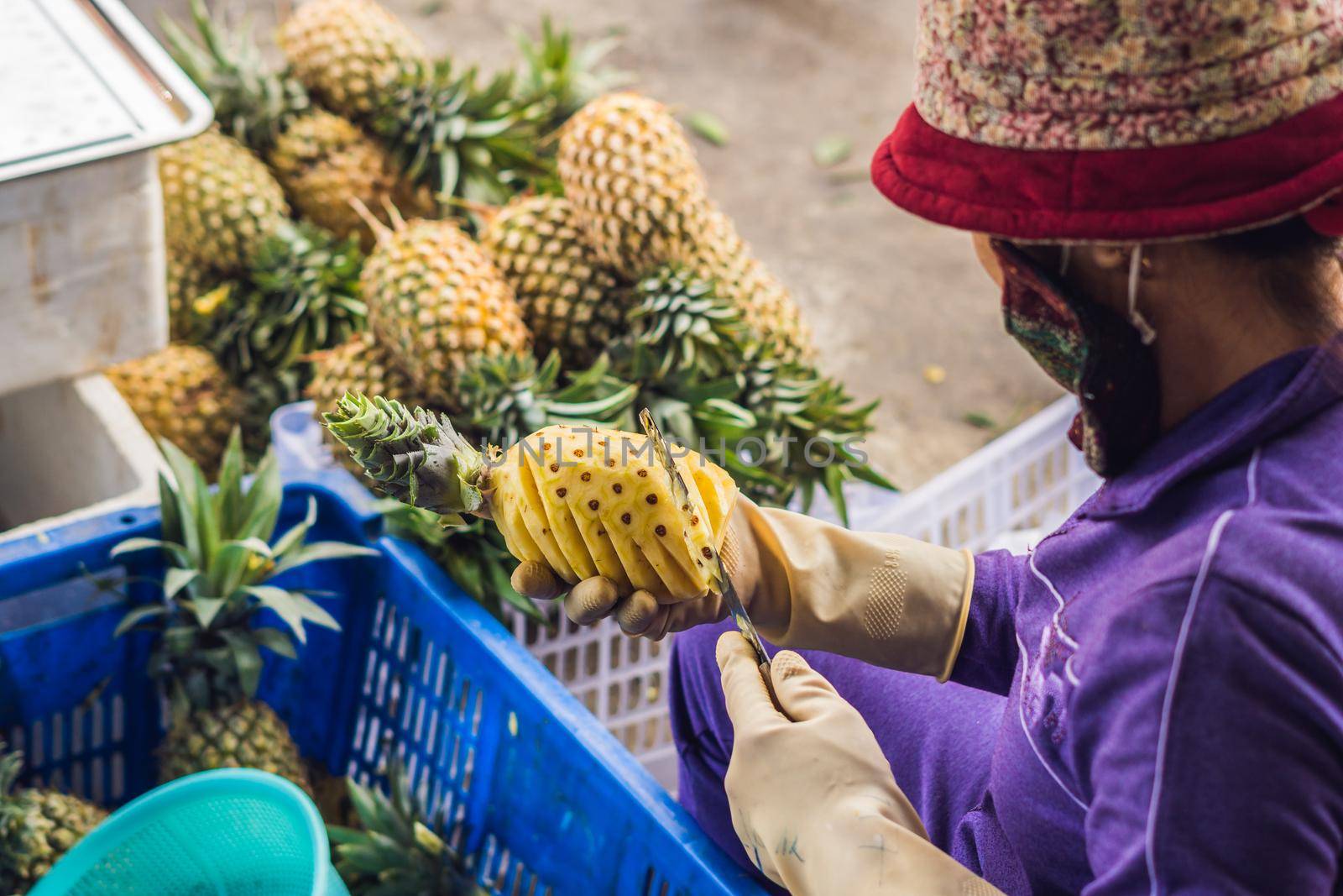 A Vietnamese woman is cleaning pineapple in the Vietnamese market. Asian cuisine concept by galitskaya