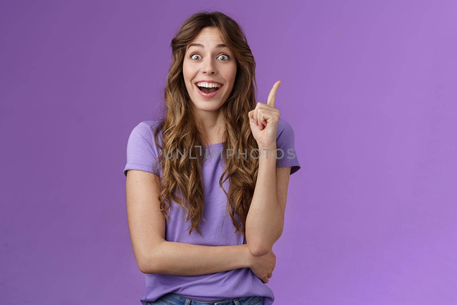 Excited cheerful happy creative smart girl raise index finger eureka gesture smiling broadly stare camera thrilled got excellent idea share suggestion think up perfect solution purple background by Benzoix