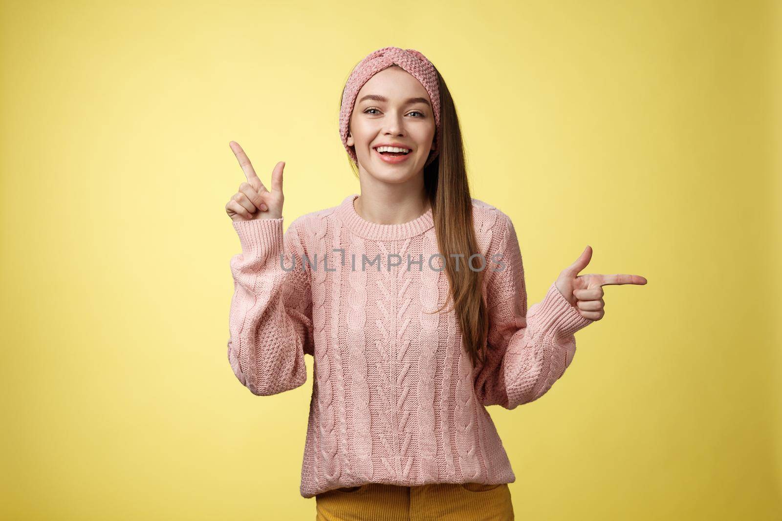 Pick what want. Charismatic cheerful young female student in headband, sweater pointing up, indicating right smiling cute, promoting advertisement showing opportunities and choices over white wall.
