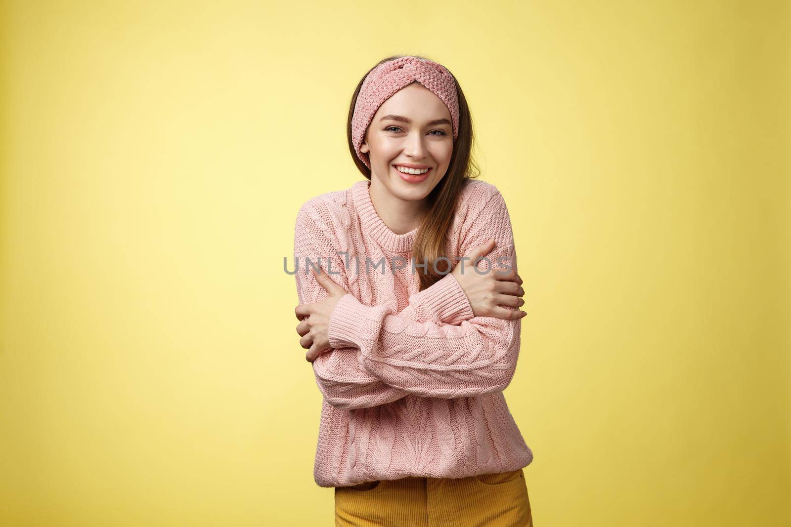 Getting chilly, better put on coat. Charming cute young tender european woman wearing sweater embracing body cross arms over chest, hugging herself to warm-up feeling cold, trembling, smiling.