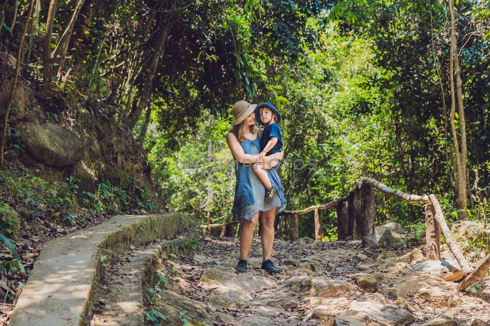 Mom and son are walking on the forest road.