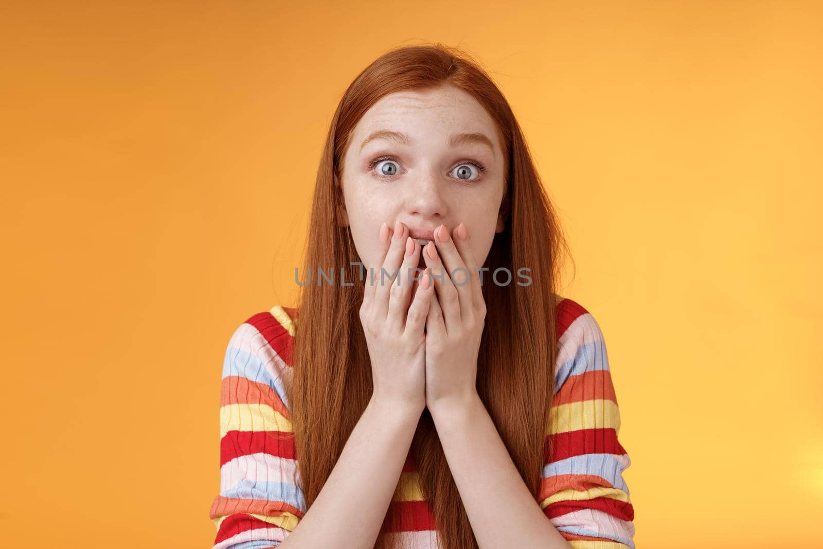 Excited shocked redhead speechless girl like gossiping standing emotional astonished hear amusing story gasping full disbelief cover mouth palm amazed posing orange background impressed.